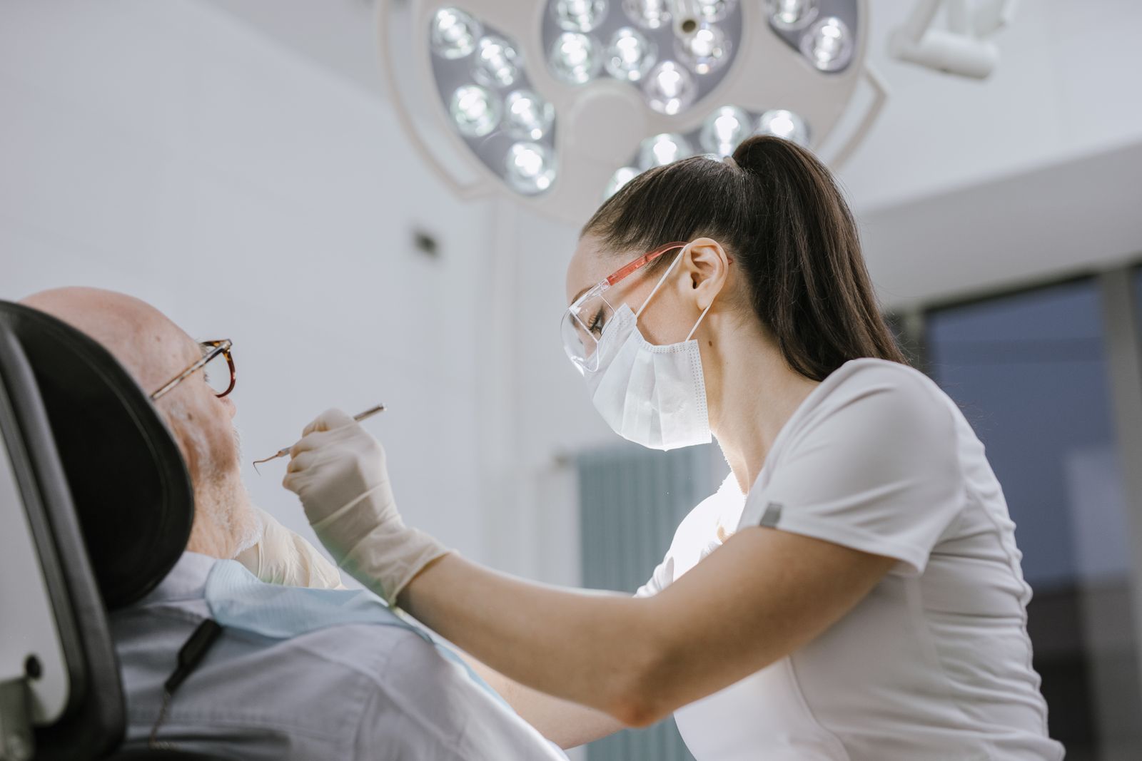 Dentista feminina atendendo um paciente em um consultório odontológico moderno com iluminação clara.